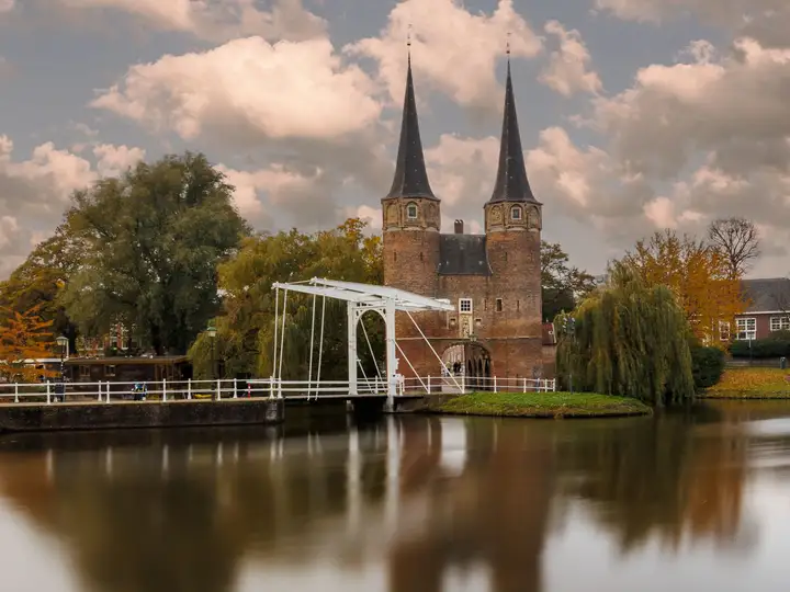 The twin brick towers of the Oostpoort gate in Delft reflected in still water